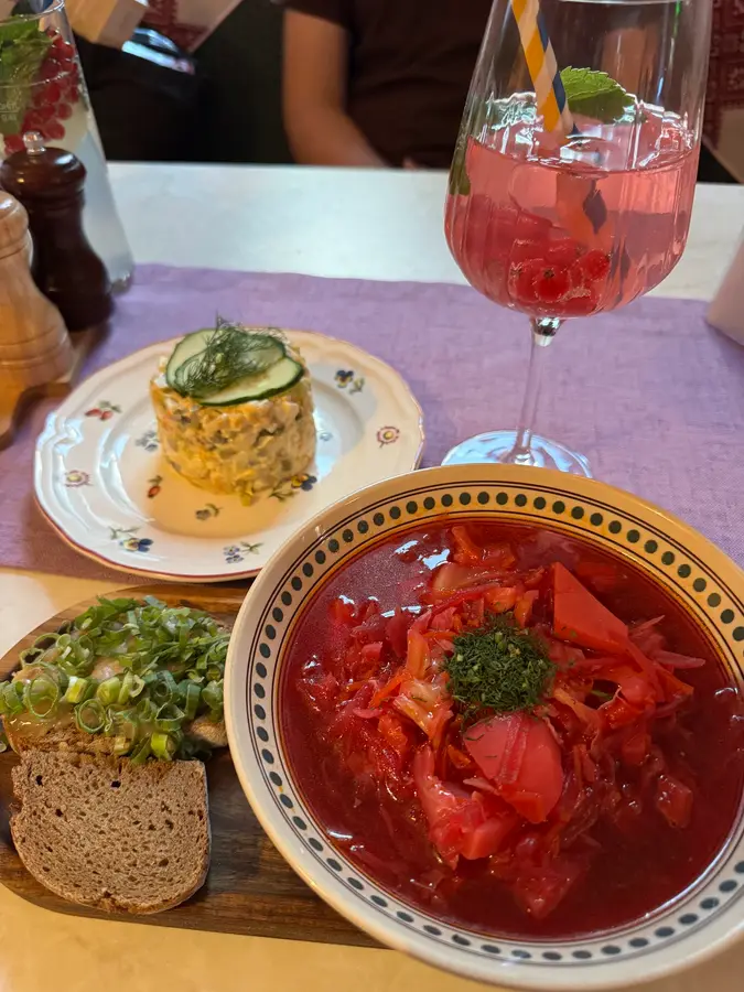 Borschtsch, Schuba-Salat und ein rosa Getränk auf einem lila Tischläufer